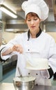 Pretty focused head chef finishing a cake with icing Royalty Free Stock Photo