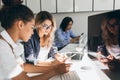 Pretty freelance copywriter texting message on phone while her colleagues typing on keyboards. Indoor portrait of young Royalty Free Stock Photo