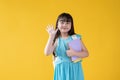A pretty and friendly little Asian schoolgirl is raising her hand and saying hi to her friends Royalty Free Stock Photo