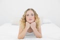 Pretty frowning blonde lying on bed looking at camera