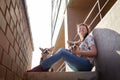 Pretty funny girl with small nice dog big wall of city house in a sunny day Royalty Free Stock Photo