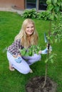 Pretty gardener woman planting apple tree