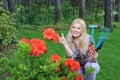 Pretty gardener woman with red flower bush