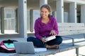 Pretty german female student learning with book and computer in front of school building Royalty Free Stock Photo