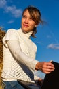 Girl on a background of blue sky in a field near a haystack in a white jacket on a bright sunny d