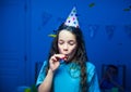 Pretty girl a birthday cap blowing a whistle at party Royalty Free Stock Photo