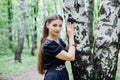 Pretty girl in black Russian dress with embroidery leaned against birch Royalty Free Stock Photo