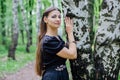 Pretty girl in black Russian dress with embroidery leaned against birch Royalty Free Stock Photo