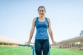 A pretty girl in a blue shirt and leggings doing sports on uneven bars looking at camera and smiling.