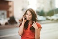 Pretty girl in casual dress is talking on a mobile phone while walking at the city street on a sunset time. Royalty Free Stock Photo