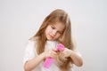 pretty girl combs tangled hair. white background.