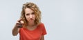 Pretty girl with curly hair looking at the camera and pointing her finger at you. Human emotions concept. Copy space Royalty Free Stock Photo