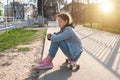 pretty girl in denim and pink sneakers sits on a penny board, a longboard . International Skateboarding Day. Royalty Free Stock Photo