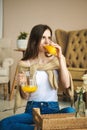 Pretty girl drinks orange juice sitting in living room