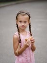 A pretty girl is eating a cheeseburger on a blurred street background. A little girl with a sandwich. Royalty Free Stock Photo
