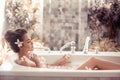 Pretty girl enjoying bath with plumeria tropical flowers. Health And Beauty. Spa Relax. Closeup Beautiful woman Bathing With