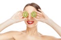 Pretty girl with fresh healthy skin hiding her eyes with kiwi, smiling and showing tip of her tongue Royalty Free Stock Photo