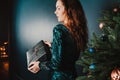 Pretty girl with gift box near Christmas tree, surprised Royalty Free Stock Photo