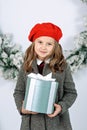Pretty girl in green dress holding present gift box near decorated Christmas tree