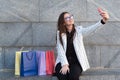 Pretty girl holding bags using smartphone and smiling