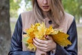 Pretty girl in jeans and coat with bright colored leaves walking in autumn park Royalty Free Stock Photo