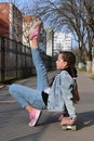 pretty girl in jeans and pink sneakers sits on a penny board and does exercises. International Skateboarding Day. Sports