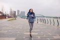 Pretty girl jogging on the river bank. Cloudy rain day Royalty Free Stock Photo