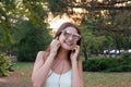 Pretty girl is listening to music in headphones outside. Favourite song. Woman is having rest in the park Royalty Free Stock Photo