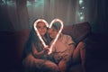 Girl and boy holding big luminous heart over dark background, waiting for love in Valentine Day