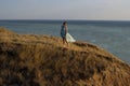 A girl in a long dress standing on a cliff by the sea