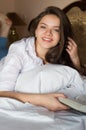 Pretty girl lying on bed with open book and Royalty Free Stock Photo