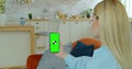 Pretty girl making video call on smartphone. Woman at Home Uses Green Mock-up Screen Smartphone. She`s Sitting On a Royalty Free Stock Photo