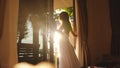 Brunette girl opens the door in the early morning during sunrise with lens flare effects Royalty Free Stock Photo