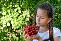 pretty girl with pigtails in white T-shirt is holding glass vase with ripe, juicy cherries. Concept of gardening and harvesting. Royalty Free Stock Photo