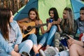 Pretty girl playing guitar tent forest friends concept.