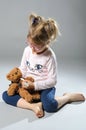 Pretty girl plays in the doctor treats a teddy bear on a gray ba Royalty Free Stock Photo