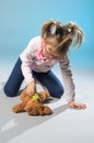 Pretty girl plays in the doctor treats a teddy bear on a gray ba Royalty Free Stock Photo