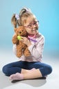 Pretty girl plays in the doctor treats a teddy bear on a gray ba Royalty Free Stock Photo