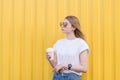 Pretty girl posing for a cup of coffee in hand on a background of yellow wall