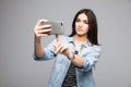 Pretty girl presses a finger on a touchscreen phone on gray background Royalty Free Stock Photo
