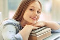 Pretty girl resting her chin on pile of books Royalty Free Stock Photo