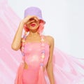 Pretty Girl 90s party style posing in studio. Trendy pink jumpsuit, bucket hat and pink hair. Fashion unicorn Lady vibes Royalty Free Stock Photo