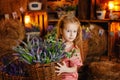 A pretty girl sits on the hay among baskets of lavender flowers. The blonde girl is dressed in a pink jumpsuit Royalty Free Stock Photo