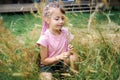 Pretty girl sitting on grass and collecting small wildflowers