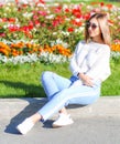 Pretty girl sitting near the flowerbed