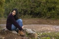 Pretty girl sitting on a rock and looking at camera