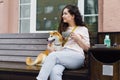 Pretty girl sitting in street cafe with cup of tea and shiba inu dog smiling Royalty Free Stock Photo