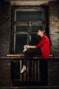 Pretty girl sitting on window sill  in the room with grunge brick walls Royalty Free Stock Photo