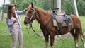 Pretty girl smiles stroking smooth velvety bay horse hair Royalty Free Stock Photo