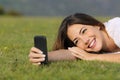 Pretty girl smiling using a smart phone lying on the grass